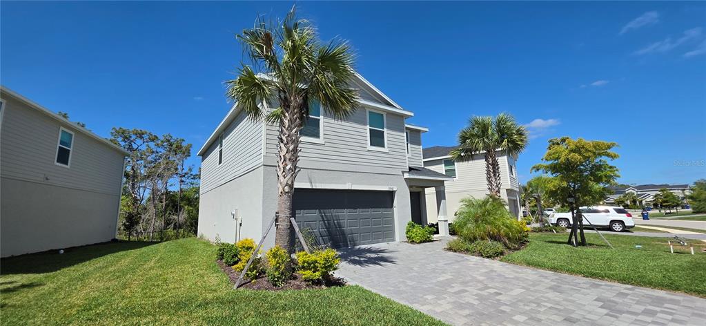 A two-story house with light gray siding, a two-car garage, and palm trees — 13961 LILAC SKY TERRACE, BRADENTON, FL