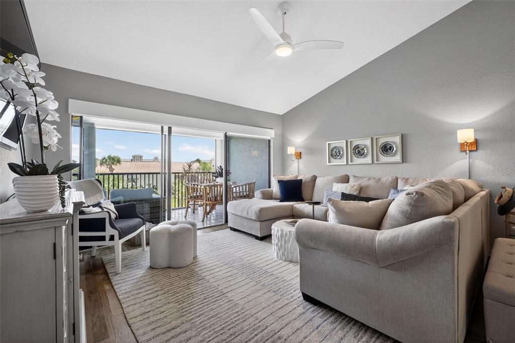 A living room features a large sectional sofa, a ceiling fan, and a balcony view — 443 BOUCHELLE DRIVE UNIT 302, NEW SMYRNA BEACH, FL