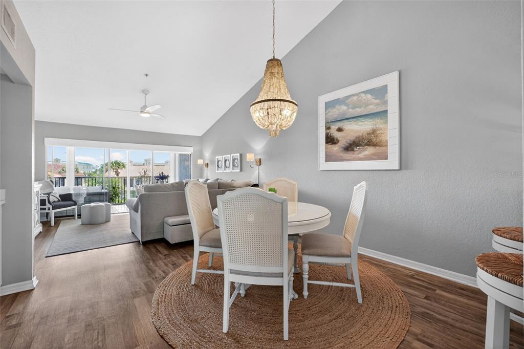 A dining area with a round table and chandelier sits adjacent to a living room — 443 BOUCHELLE DRIVE UNIT 302, NEW SMYRNA BEACH, FL