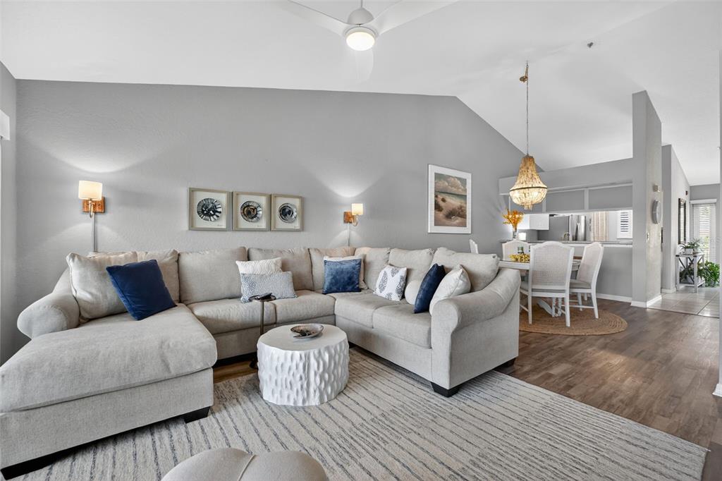 A living room features a large sectional sofa, a textured coffee table, and vaulted ceilings — 443 BOUCHELLE DRIVE UNIT 302, NEW SMYRNA BEACH, FL