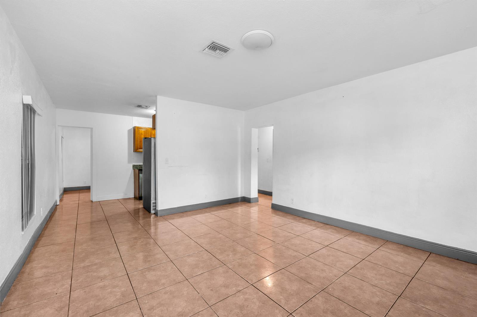 An empty room with white walls, gray baseboards, and light brown tile flooring — 124 SW 10th Avenue, Boynton Beach FL 33435, BOYNTON BEACH, FL
