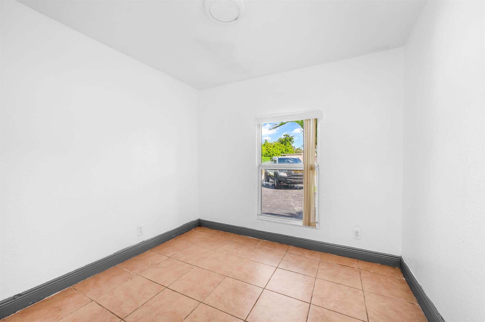 An empty room with white walls, dark gray baseboards, tiled floors, and a single window — 124 SW 10th Avenue, Boynton Beach FL 33435, BOYNTON BEACH, FL