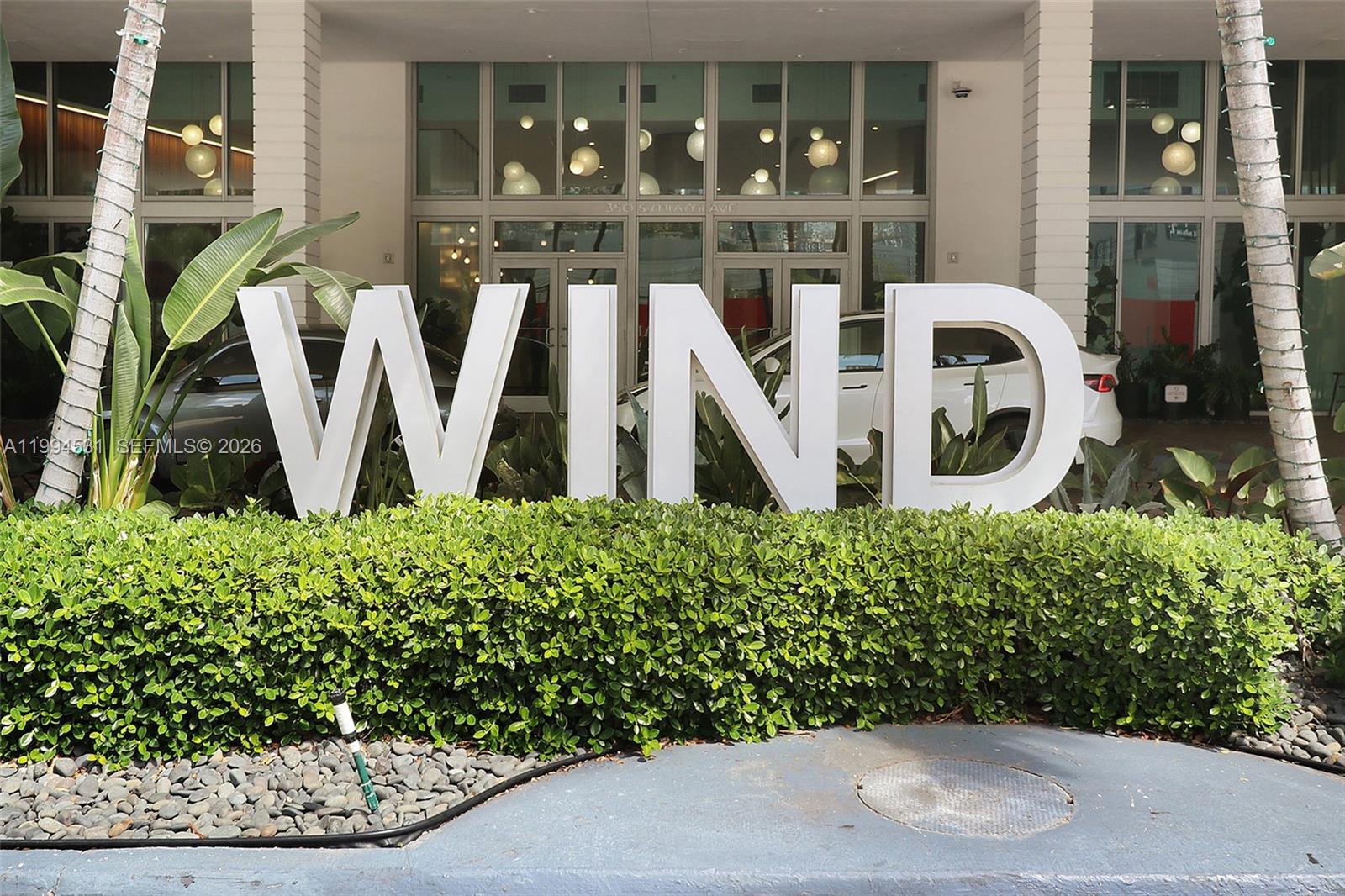 Large white letters spelling WIND stand in front of a building entrance with landscaping — 350 S Miami Ave # 4110, Miami FL 33130, MIAMI, FL