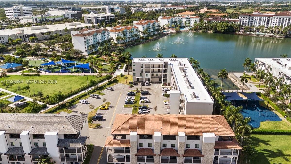An aerial view shows multi-story apartment buildings, a lake with fountains, and a playground — 4636 NW 84th Ave # 13, Doral FL 33166, DORAL, FL