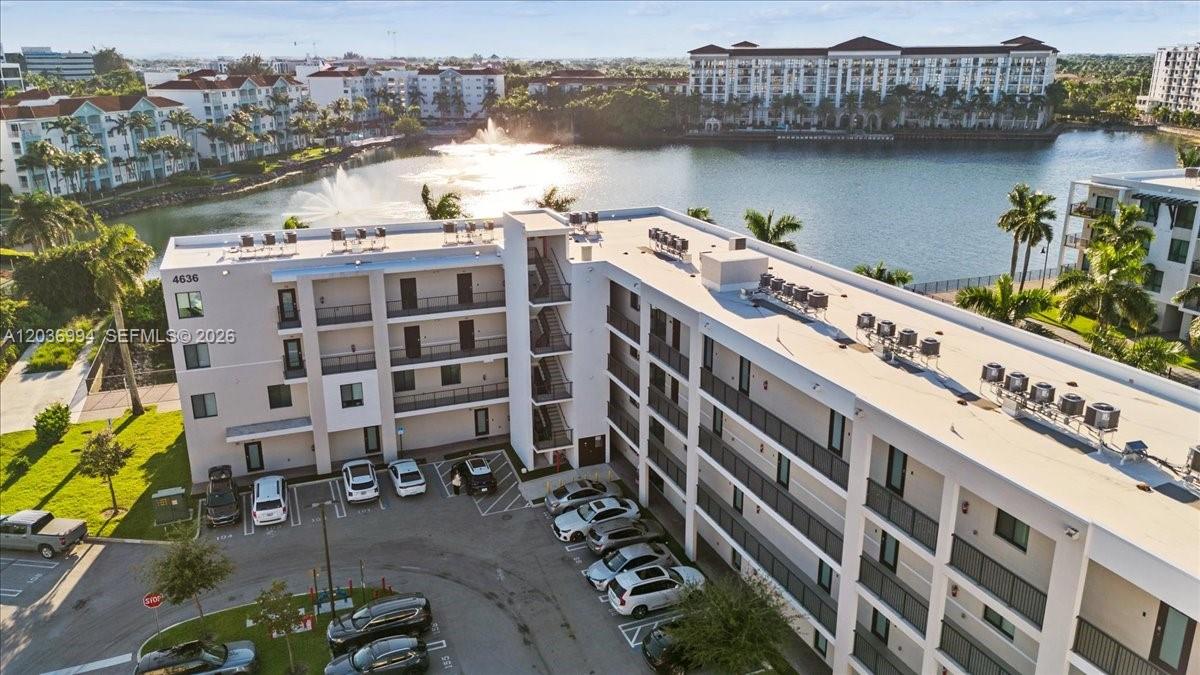 An aerial view shows a multi-story apartment building with a parking lot and lake — 4636 NW 84th Ave # 13, Doral FL 33166, DORAL, FL