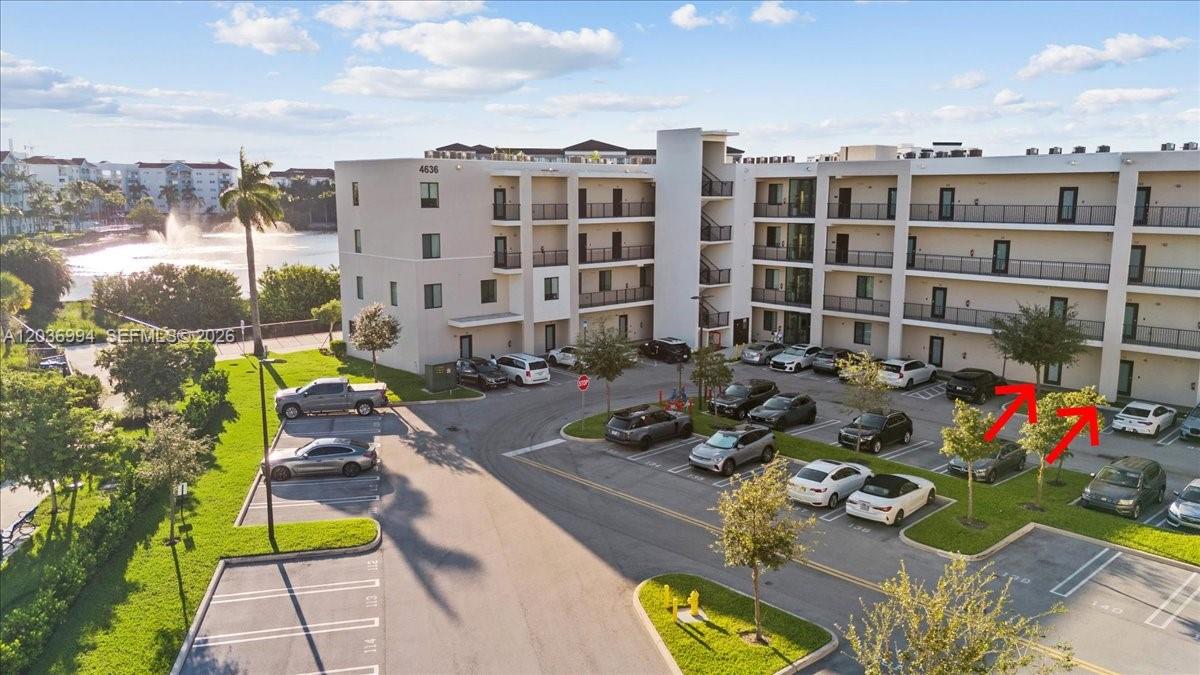 An aerial view shows a multi-story apartment building with a parking lot and lake — 4636 NW 84th Ave # 13, Doral FL 33166, DORAL, FL