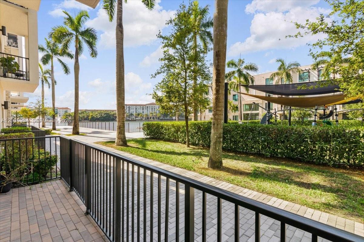 A view from a patio overlooking a grassy area, palm trees, and a playground — 4636 NW 84th Ave # 13, Doral FL 33166, DORAL, FL