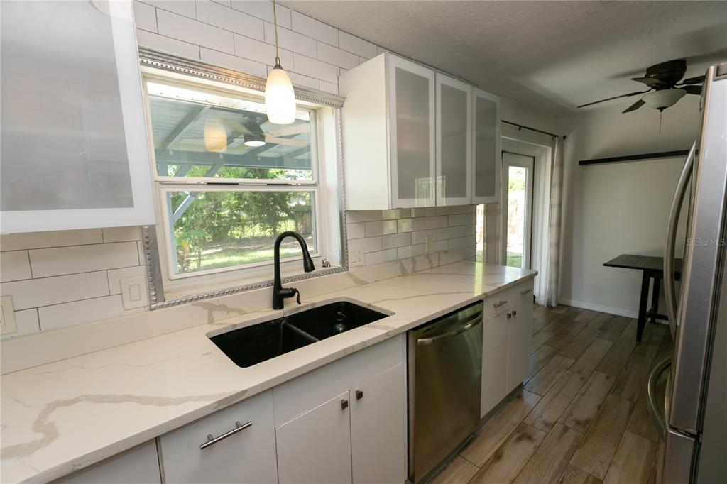 A kitchen features white cabinets, marble-look countertops, a black sink, and subway tile backsplash — 3562 BOUGAINVILLEA DRIVE, WINTER PARK, FL