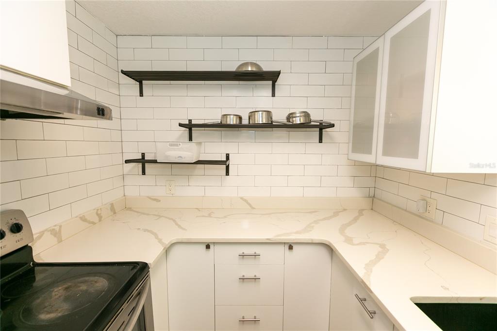 A kitchen features white subway tile walls, open shelving, and light-colored marble-patterned countertops — 3562 BOUGAINVILLEA DRIVE, WINTER PARK, FL