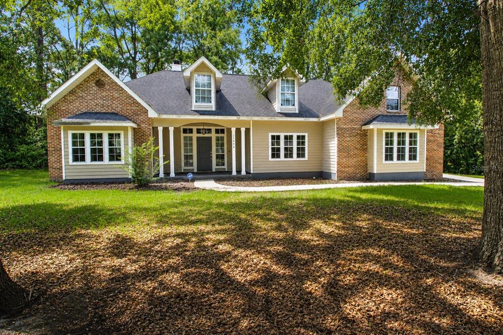 A single-story brick and tan siding house with a dark shingled roof and dormer windows — 11444 NW 18TH LANE, GAINESVILLE, FL