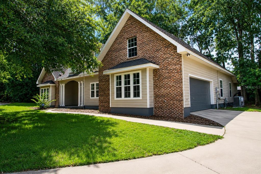 A two-story house with a brick and tan siding exterior, a garage, and a lawn — 11444 NW 18TH LANE, GAINESVILLE, FL