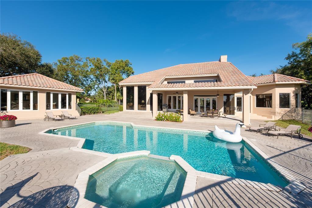 A backyard features a swimming pool, a hot tub, and a tan house with tile roofs — 3190 Willow Lane, Weston FL 33331, WESTON, FL