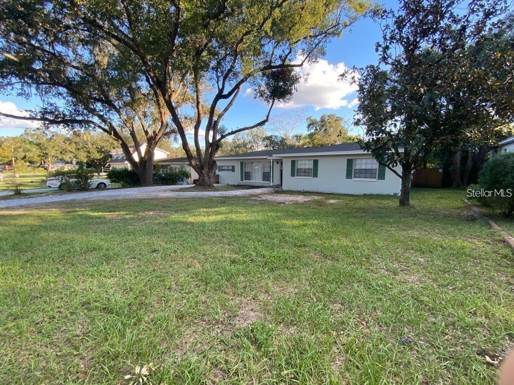 A single-story house with a light-colored exterior and green shutters sits behind large trees — 309 DEER PARK AVENUE, TAMPA, FL