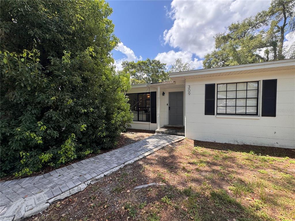A white single-story house features a gray front door and a paved walkway — 309 DEER PARK AVENUE, TAMPA, FL