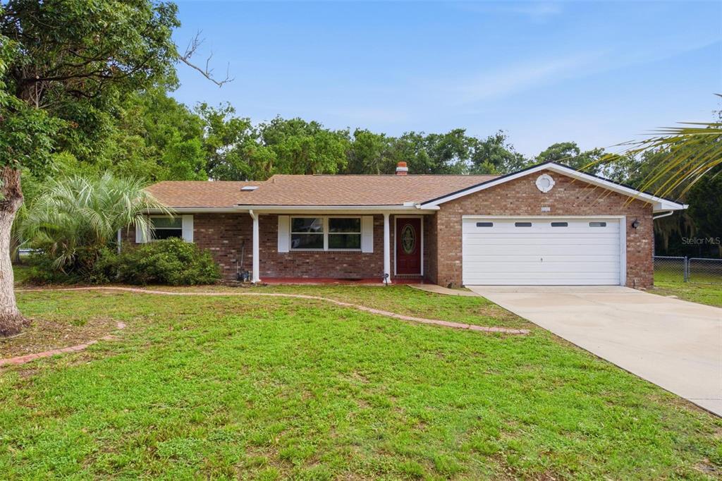A single-story brick house with a white garage door and a front lawn — 5118 MAGNOLIA TERRACE, FRUITLAND PARK, FL