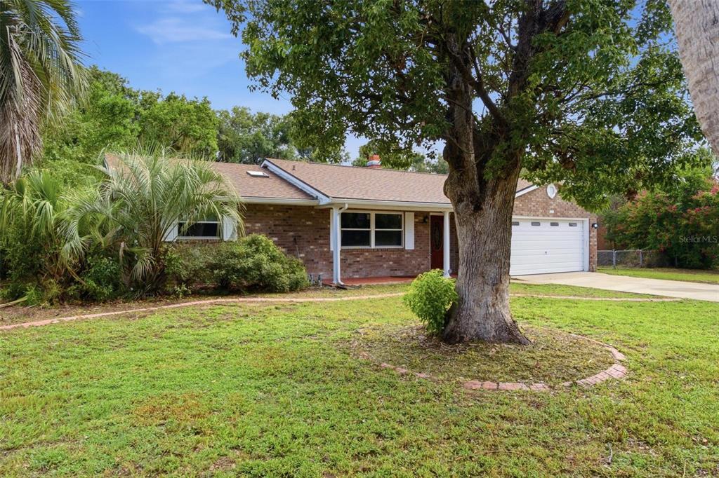 A single-story brick house with a two-car garage and a large tree in the yard — 5118 MAGNOLIA TERRACE, FRUITLAND PARK, FL