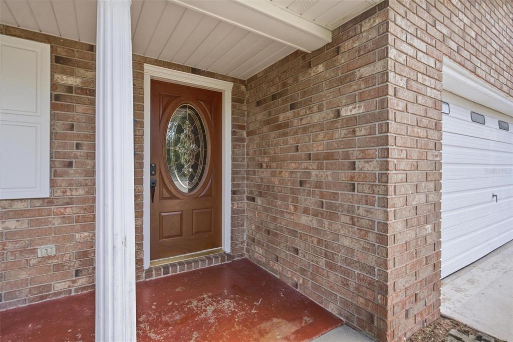 A brick house exterior features a brown front door with a glass oval insert — 5118 MAGNOLIA TERRACE, FRUITLAND PARK, FL