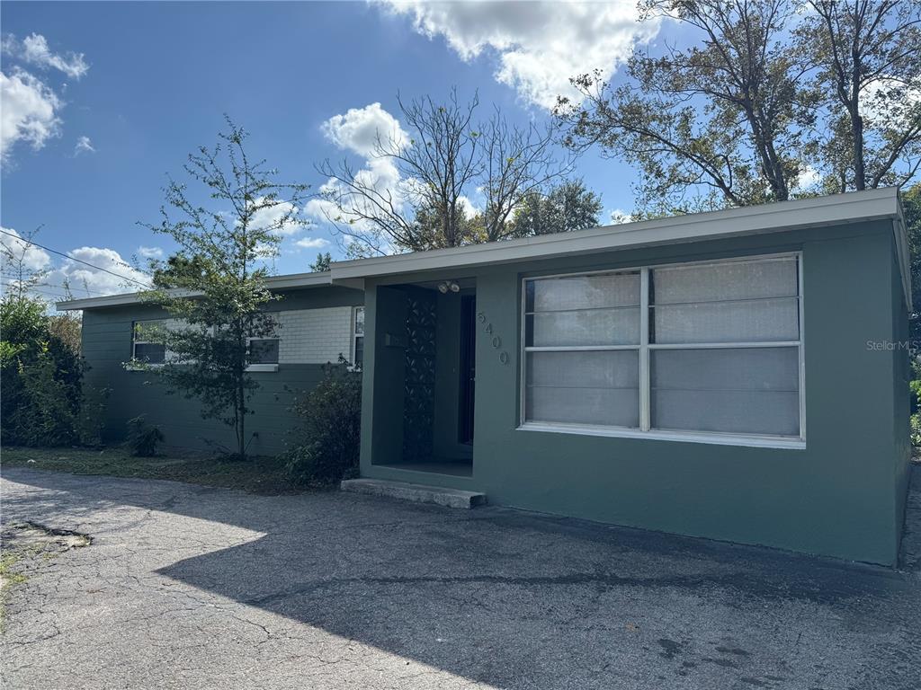 A single-story house with green exterior walls, a flat roof, and a paved driveway — 5400 SAN JUAN BOULEVARD, ORLANDO, FL
