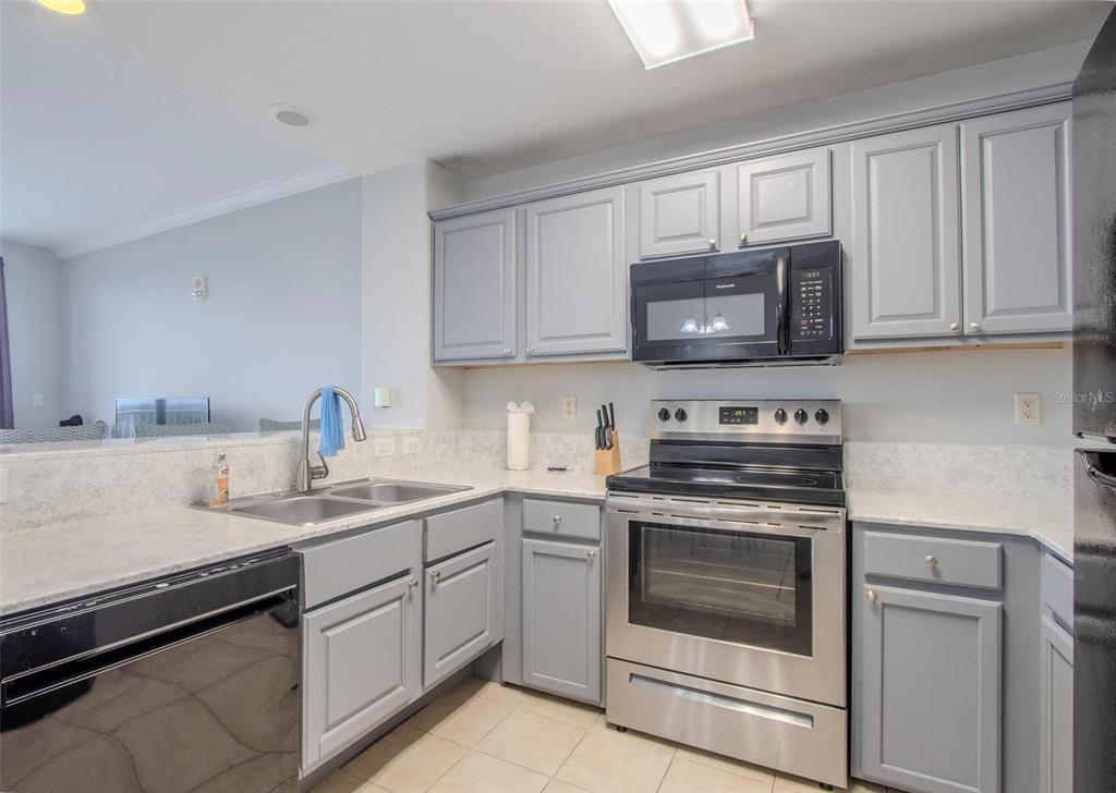 A kitchen with gray cabinets, stainless steel appliances, and light-colored countertops — 13415 BLUE HERON BEACH DRIVE UNIT 407, ORLANDO, FL