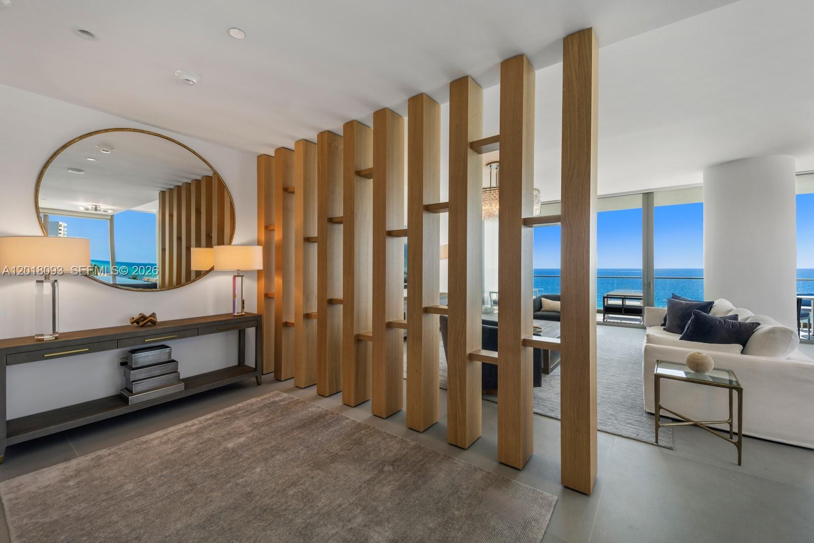 A modern living room features a wooden slat room divider and a view of the ocean — 2000 S Ocean Dr # 7B, Hallandale Beach FL 33009, HALLANDALE BEACH, FL