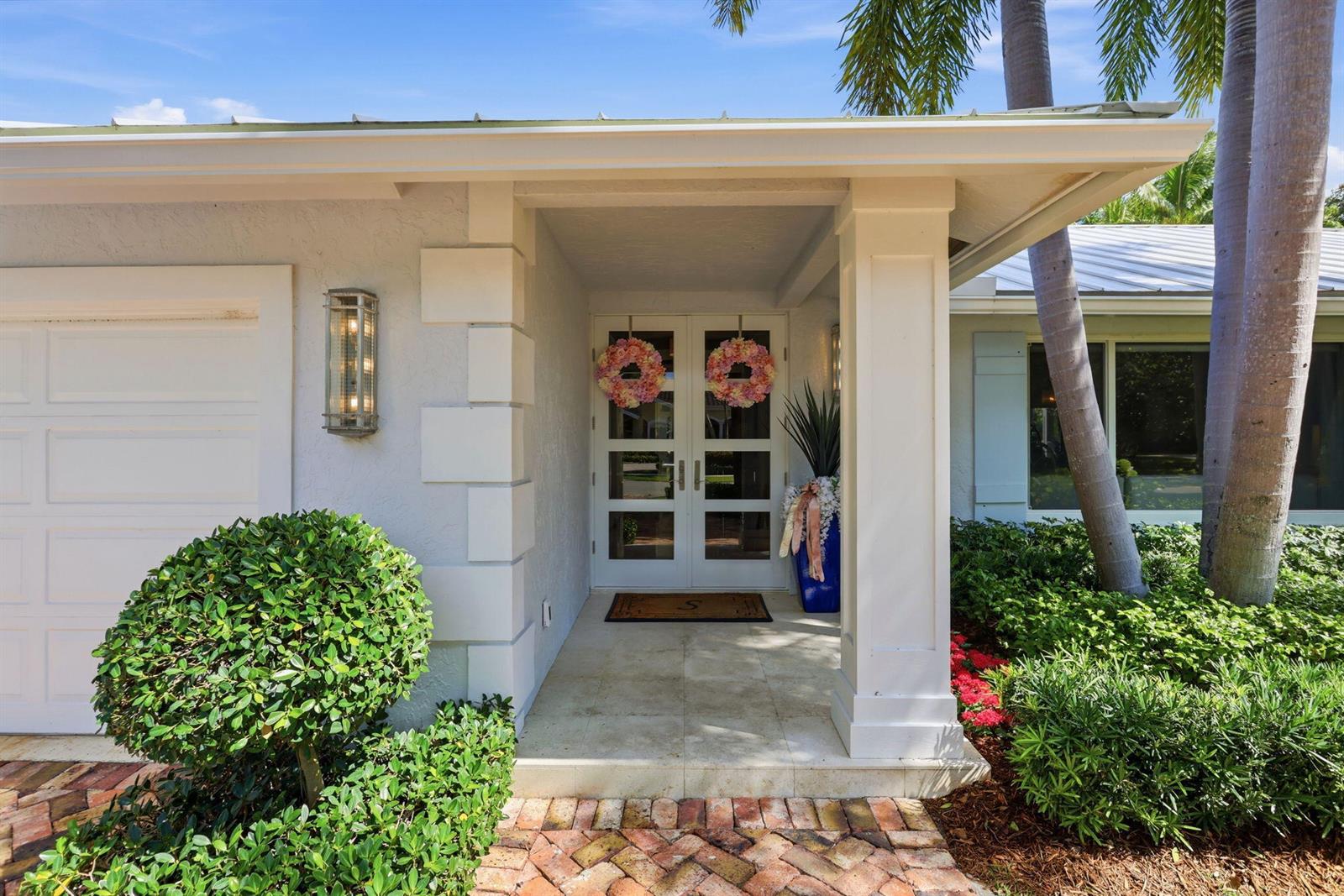 The exterior of a house features a white double front door, a brick walkway, and palm trees — 2151 NW 30th Road, Boca Raton FL 33431, BOCA RATON, FL