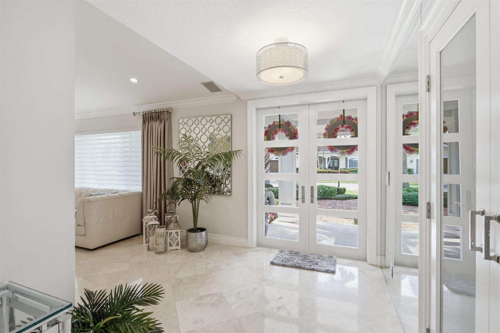 A bright entryway features white double doors, marble flooring, a potted plant, and mirrored decor — 2151 NW 30th Road, Boca Raton FL 33431, BOCA RATON, FL