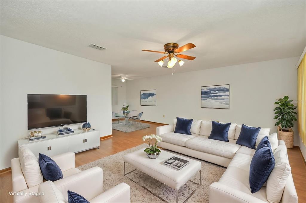 A living room features a white sectional sofa, a television, and wood flooring — 9881 SW 101ST PLACE, OCALA, FL