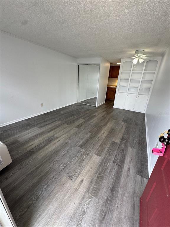 A room with wood-look flooring, a mirrored closet, and a white built-in shelving unit — 420-420 MILLS STREET UNIT 25, LEESBURG, FL