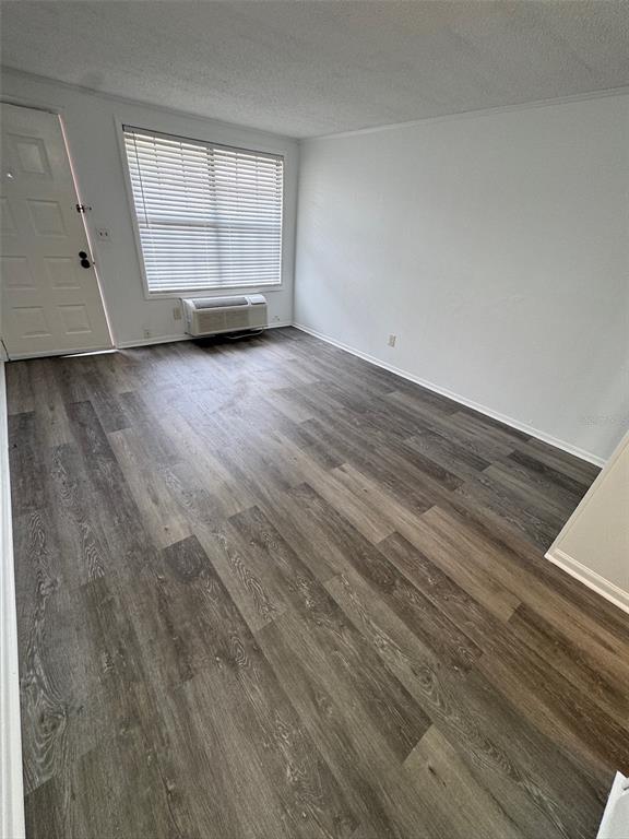 An empty room features gray wood-look flooring, white walls, a window with blinds, and an AC unit — 420-420 MILLS STREET UNIT 25, LEESBURG, FL
