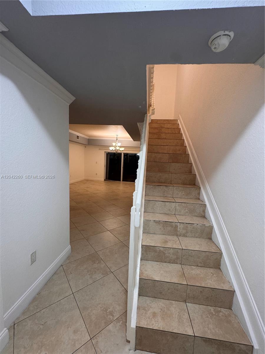A tiled staircase with a white railing leads upward next to an open living area — 8810 W Flagler St # 11, Miami FL 33174, MIAMI, FL