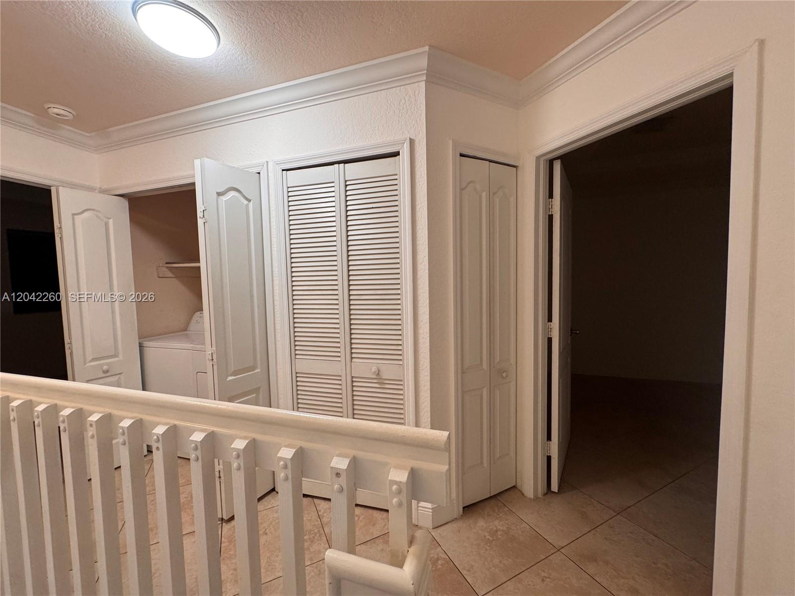 A hallway features a laundry closet, louvered doors, and an open doorway to a room — 8810 W Flagler St # 11, Miami FL 33174, MIAMI, FL