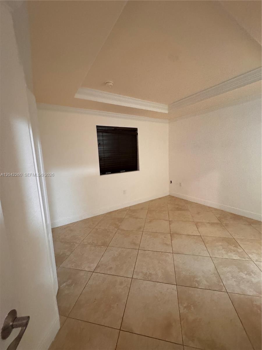 An empty room features a tray ceiling, tiled floors, and a single window with blinds — 8810 W Flagler St # 11, Miami FL 33174, MIAMI, FL