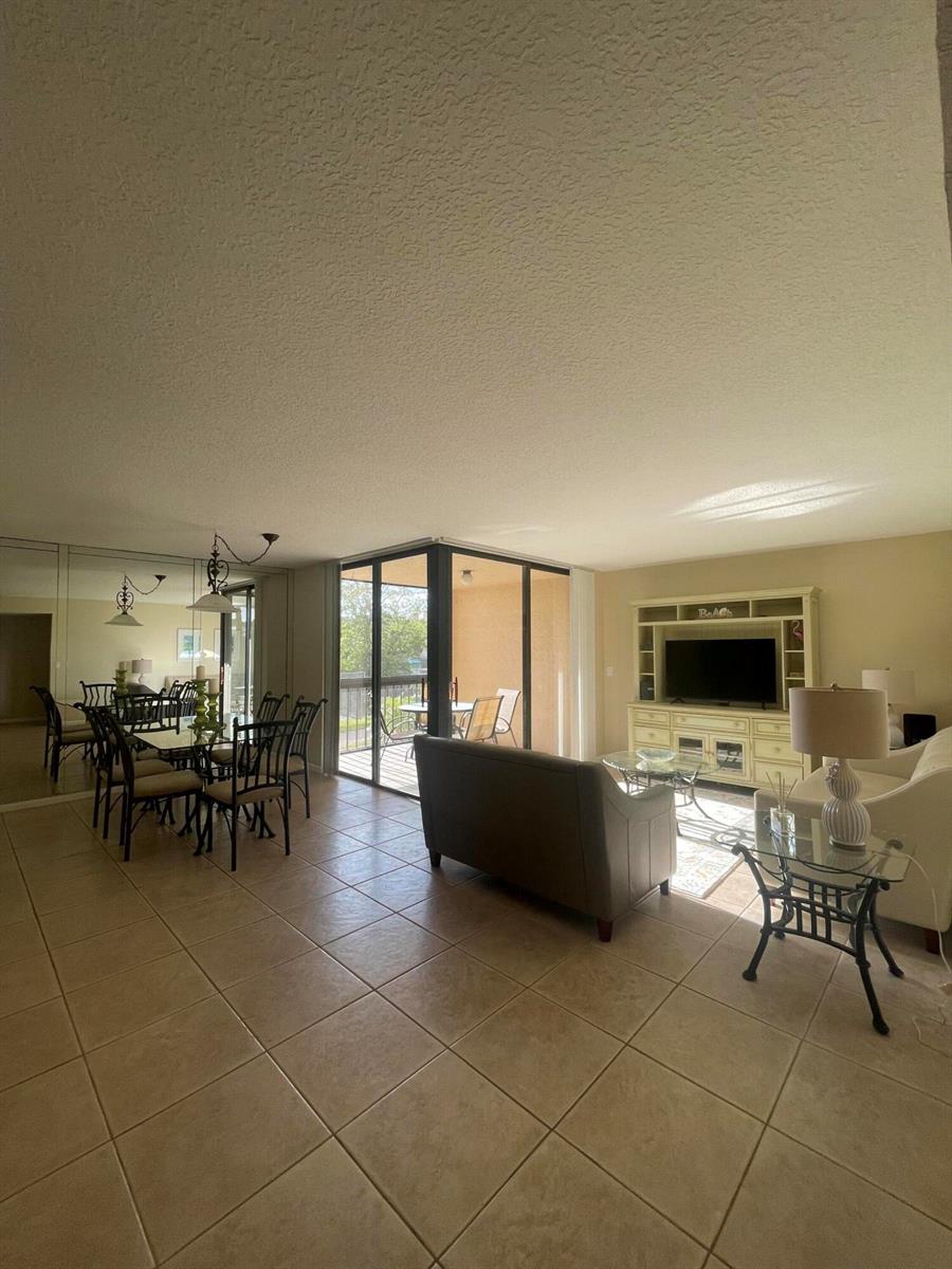 A living and dining area with tile floors, a glass-topped table, and a balcony view — 450 Egret Circle # 9203, Delray Beach FL 33444, DELRAY BEACH, FL