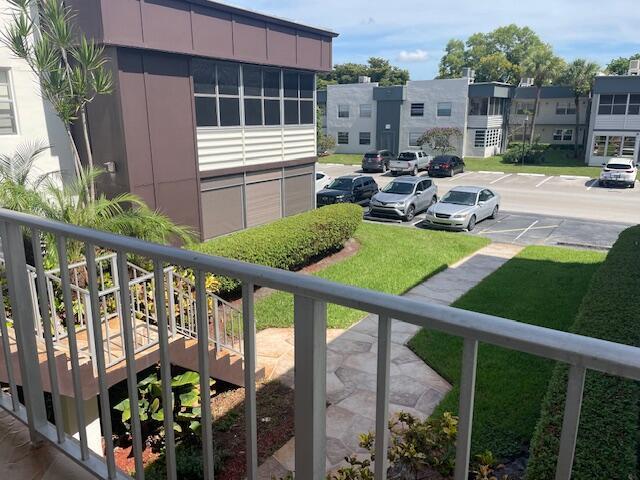 An elevated view from a balcony overlooking a parking lot, apartment buildings, and a walkway — 705 Normandy O # 705, Delray Beach FL 33484, DELRAY BEACH, FL