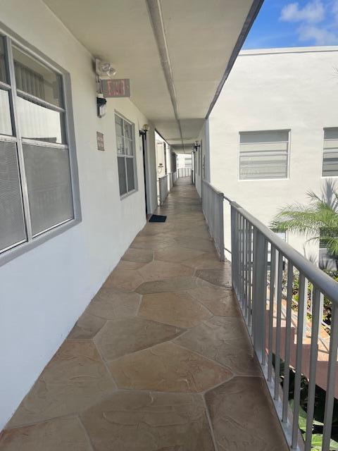 An outdoor apartment walkway features stone-patterned flooring and a white metal railing — 705 Normandy O # 705, Delray Beach FL 33484, DELRAY BEACH, FL