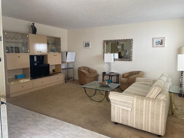 A living room features beige carpet, a large wall unit, a sofa, and two armchairs — 705 Normandy O # 705, Delray Beach FL 33484, DELRAY BEACH, FL