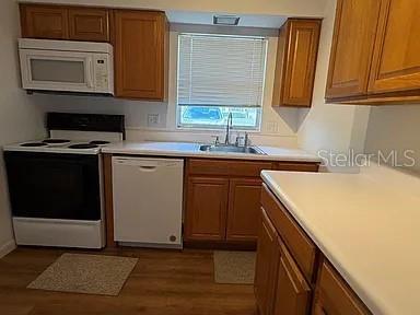 A kitchen features wooden cabinets, white appliances, a sink, and light-colored countertops — 120B E MINNESOTA AVENUE UNIT B, DELAND, FL