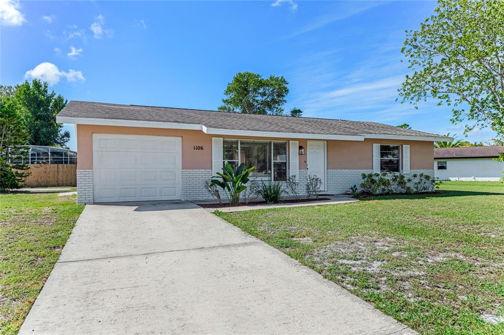 A single-story house with a tan exterior, white brick accents, and a concrete driveway — 1106 BLUEBERRY DRIVE, PORT ORANGE, FL