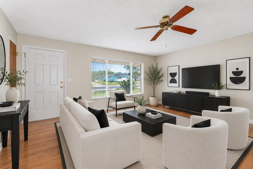 A living room features a white sofa, two armchairs, a television, and a ceiling fan — 1106 BLUEBERRY DRIVE, PORT ORANGE, FL