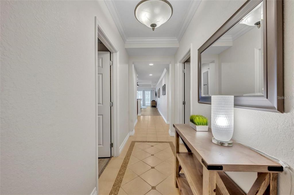 A hallway with tile flooring, a wooden console table, and a mirror leads to another room — 7659 WHISPER WAY UNIT 102, REUNION, FL