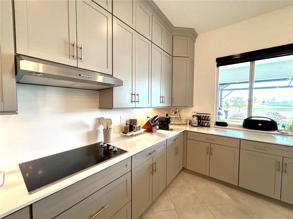 A kitchen features light gray shaker cabinets, white countertops, and a stainless steel range hood — 17510 JADESTONE COURT, VENICE, FL