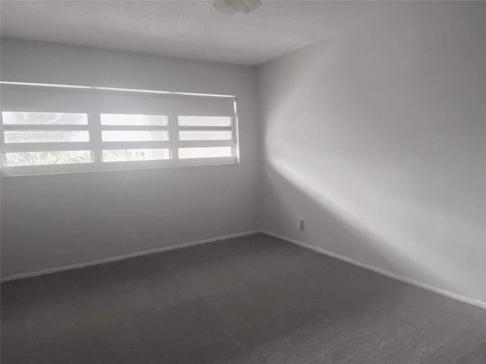 An empty bedroom features white walls, gray carpet, and a window with horizontal blinds — 2671 S Course Drive # 602, Pompano Beach FL 33069, POMPANO BEACH, FL