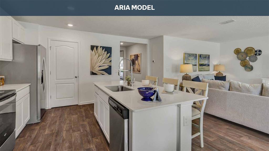 A kitchen with a white island and stainless steel appliances opens into a living area — 77 SAWDUST LANE, PALM COAST, FL
