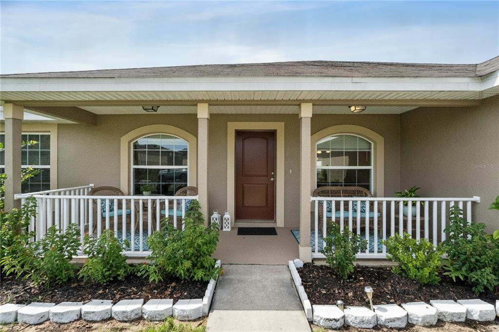 A covered front porch features a brown door, white railings, and two arched windows — 545 VICEROY COURT, KISSIMMEE, FL