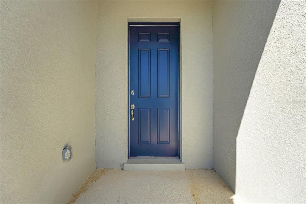 A dark blue, six-panel front door is set into a light-colored stucco entryway — 1052 LUKE AVENUE, WINTER HAVEN, FL