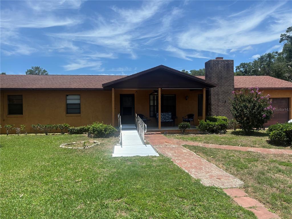 A single-story house with a brown stucco exterior, a brick chimney, and a wheelchair ramp — 2105 SW 5TH STREET, OCALA, FL