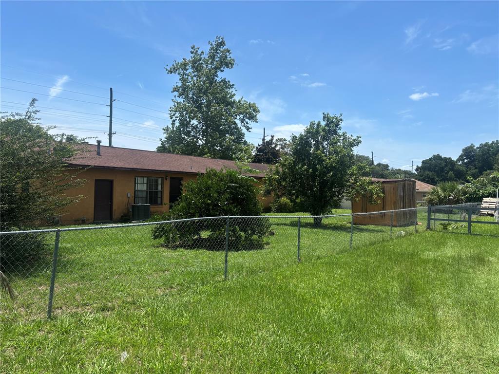 A backyard with a chain-link fence, a small shed, and a single-story house — 2105 SW 5TH STREET, OCALA, FL