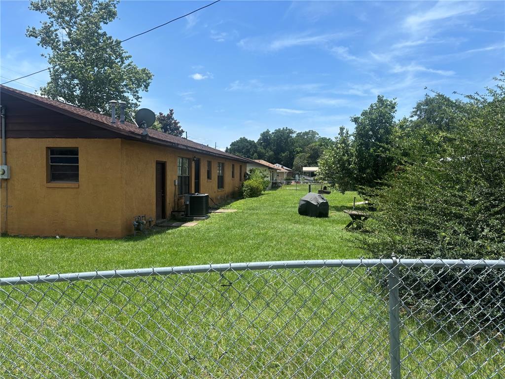 A view of the side of a yellow house with a grassy yard and fence — 2105 SW 5TH STREET, OCALA, FL
