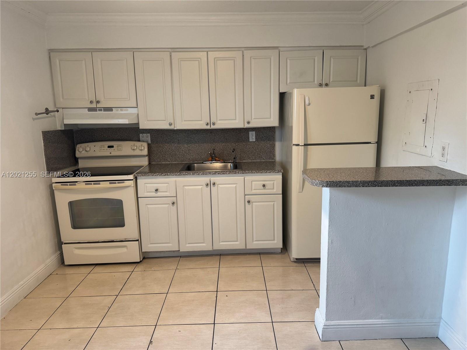 A kitchen features white cabinetry, a white stove, a refrigerator, and a granite countertop — 11 SW 32nd Ave # 1, Miami FL 33135, MIAMI, FL