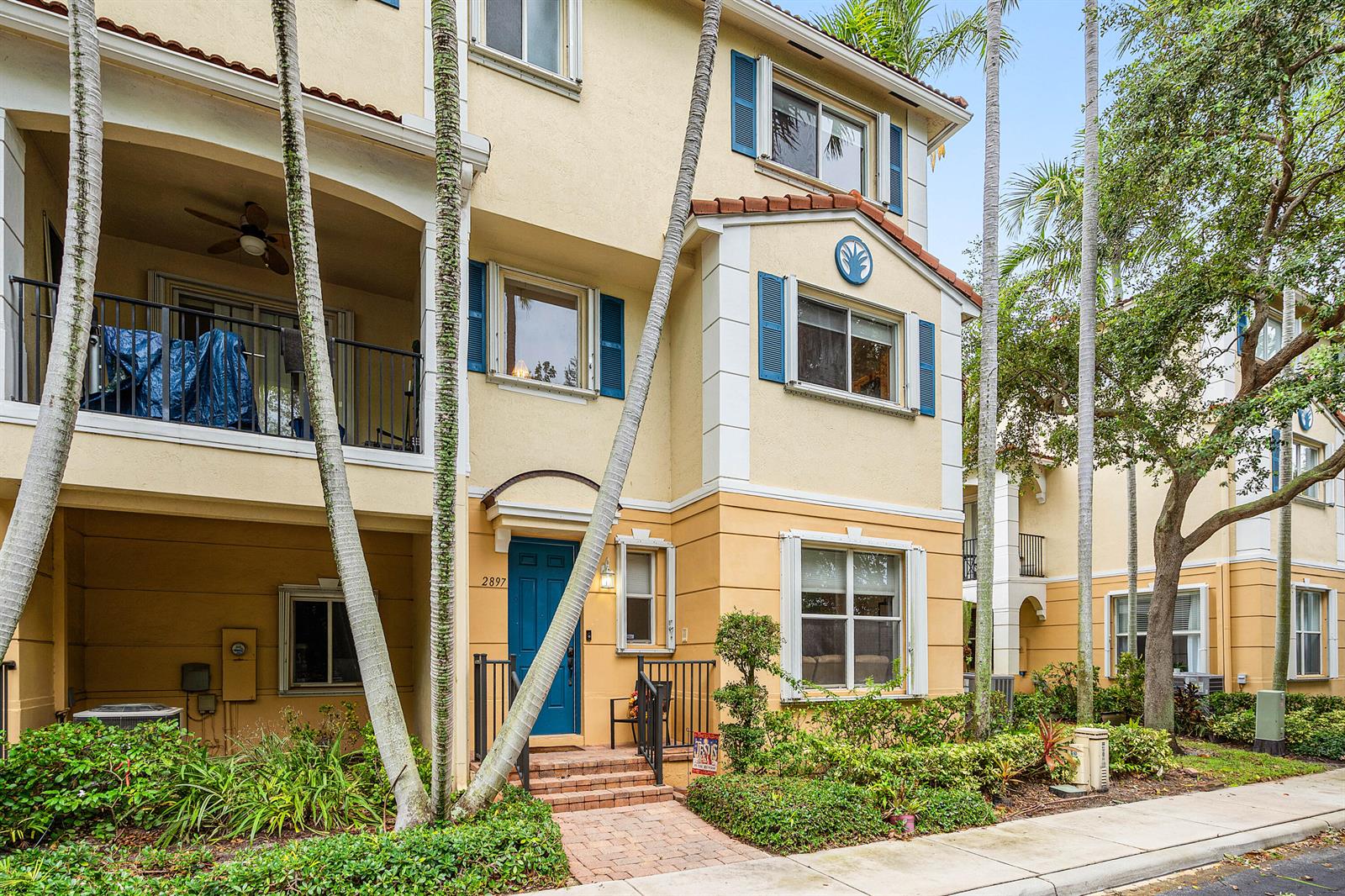 A three-story townhouse with a blue front door, a balcony, and palm trees in front — 2897 S Greenleaf Circle, Boynton Beach FL 33426, BOYNTON BEACH, FL